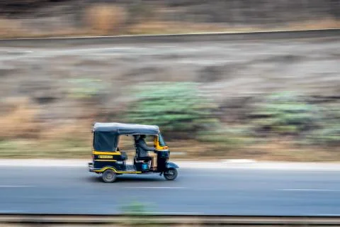 A blurred background image of three wheeler autorikshaw speeding on a motorwa Stock Photos