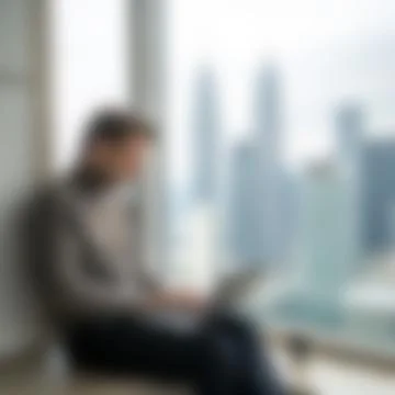 Blurred Background of Man Sitting by Window with City View using Laptop Stock Photos
