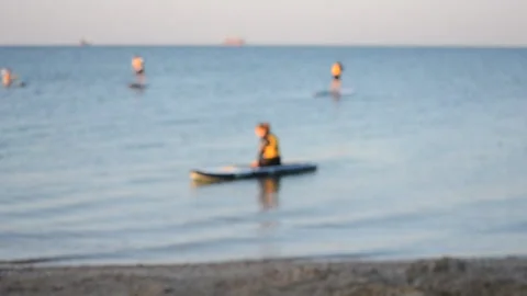 Blurred background. Many people standing and sitting swim on sup boards Stock Footage 150258363