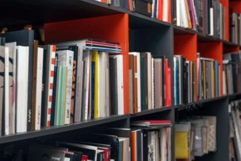 Blurred background with multi-colored books and catalogs on the shelves Stock Photos