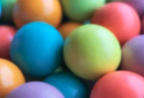 Blurred background from multicolored bright small wooden balls of blue, yellow Stock Photos