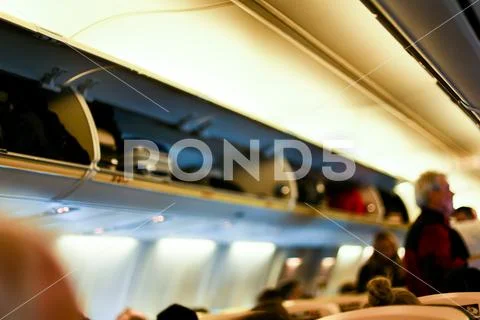 Blurred background photo of airplane interior and passengers with bags on Stock Photos