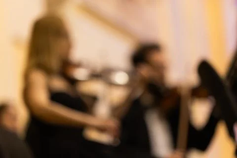 Blurred background shot of violinists playing instruments in a symphony orc.. Stock Photos