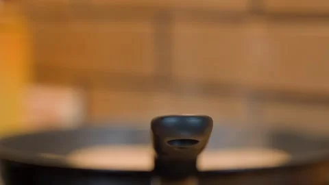 Blurred background as something cooks and steams in a pan Stock Footage 310765799