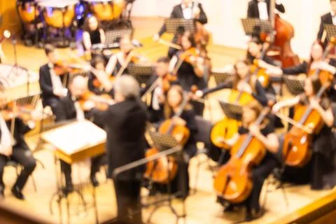 Blurred background of a symphony orchestra with conductor performing on sta.. Stock Photos