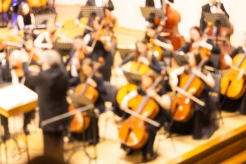 Blurred background of a symphony orchestra with conductor performing on sta.. Stock Photos