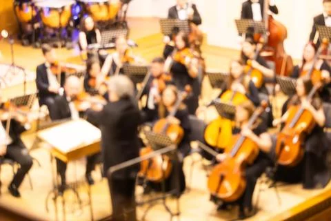 Blurred background of a symphony orchestra with conductor performing on sta.. Stock Photos