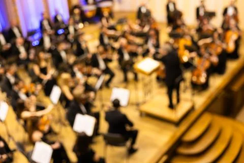 Blurred background of a symphony orchestra with conductor performing on sta.. Stock Photos