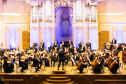 Blurred background of a symphony orchestra with conductor performing on sta.. Stock Photos