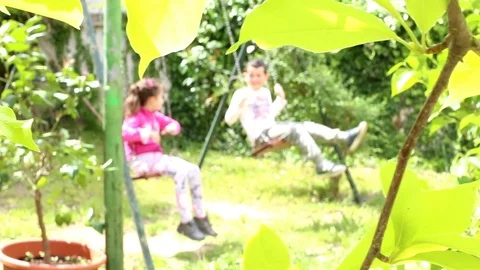 Blurred background of two child on a swing in the garden Stock Footage 74623405