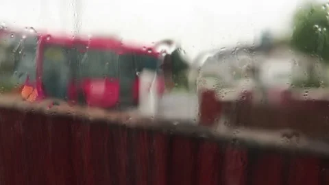 Blurred Background Viewed From Wet Rained Window With Red Bus Going Past. Stock Footage 131833508
