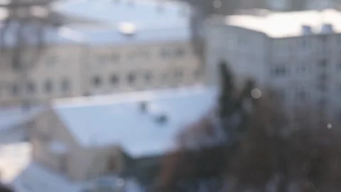 Blurred background of a winter cityscape with falling snowflakes on a sunny day. Video stock 326425052
