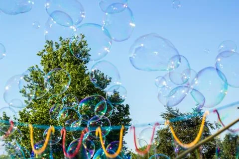 Blurred big soap bubbles flying in blue sky, abstract background Stock Photos