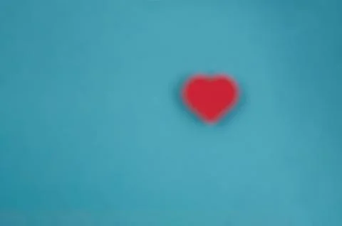 Blurred blue background with blurred red heart Stock Photos
