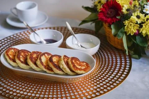 Blurred breakfast with homemade cheesecakes, tea and raspberry jam Foto stock