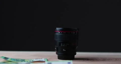 Blurred Camera lens being showered in money with simple black background Stock Footage 237546271