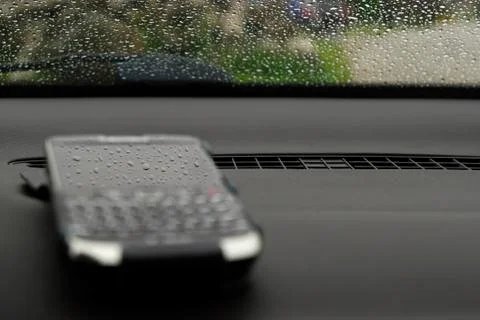 Blurred cell phone with sharp rain drops reflection in its screen Stock Photos