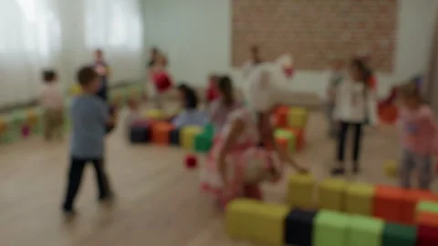 Blurred children playing in bright indoor classroom with colorful blocks and Stock Footage 345264081