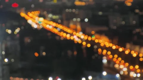 Blurred city night view with glowing streetlights and moving traffic, creating a 스톡 동영상 295530962