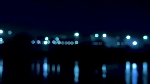 Blurred cityscape with glowing lights reflecting on water under a deep blue.. Stock-Footage 340220761