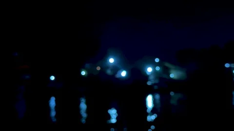 Blurred cityscape at night with glowing blue lights reflecting on water in .. Video stock 340220663