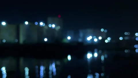 Blurred cityscape at night with glowing lights reflecting on water in a dre.. Vídeos de archivo 340052536
