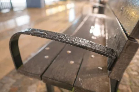 Blurred closeup bench with raindrops during evening Stock Photos