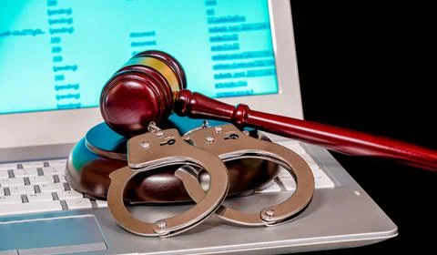 Blurred computer screen with program code visible, and shaking handcuffs Foto stock