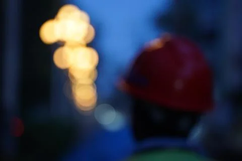 Blurred construction worker wearing a red hard hat at a site with bokeh city Stock Photos