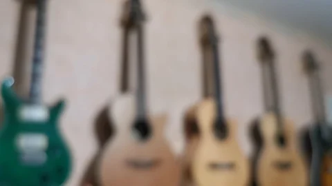 Blurred defocused guitars collection hanging on the wall 4K UHD Stock Footage 128829068