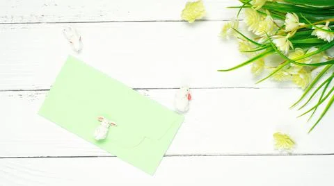Blurred Easter composition. Yellow flowers green envelop white bunny rabbits Stock Photos