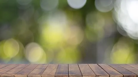 Blurred empty wooden table top with bokeh, blurred natural green background. Stock Photos