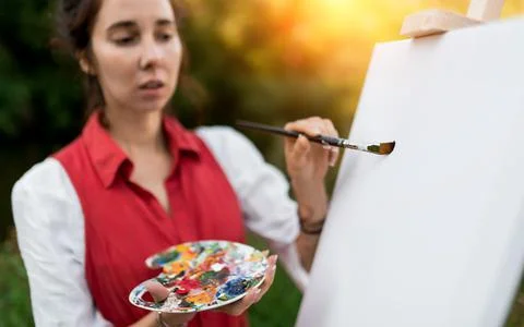 Blurred face out of focus. Close-up of a woman artist, applying first brush Stock Photos