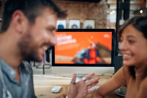 Blurred faces of young man and woman colleagues talking in front of table w.. Stock Photos