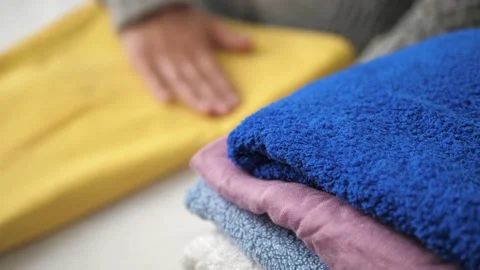 Blurred female hands neatly stack yellow dress in pile with ironed clothes. Girl Stock Footage 133545530