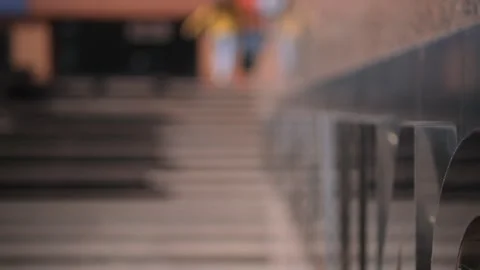A blurred figure in a yellow jacket walking up steps against a reflective wall Video stock 276589378