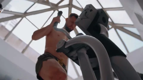 Blurred frame of the young man with a bare chest who trains at the gym on an Stock Footage 156864152