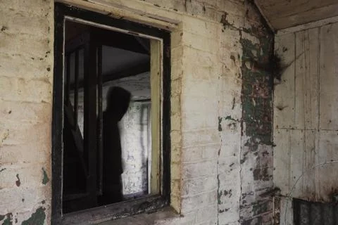 A blurred, ghostly figure. Framed in a window in a decaying old house Stock Photos