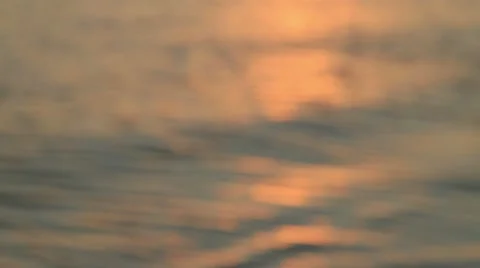 Blurred, golden waves reflect the sunset and gently roll onto a beach Stock Footage 12099536