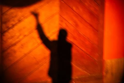 Blurred human shadow raising arm on wall Stock Photos