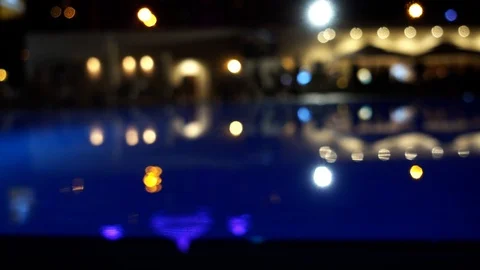 Blurred image of the blue surface of the pool and the lights of the restauran Stock Footage 94793522
