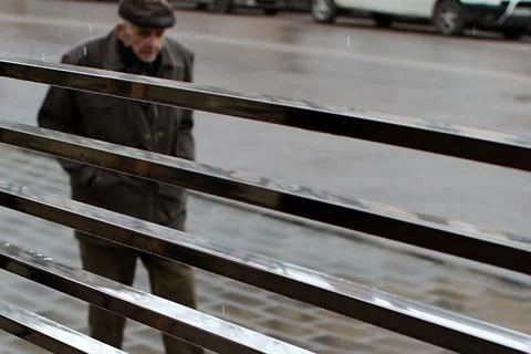 Blurred image of elderly man walking down rainy street Stock Photos
