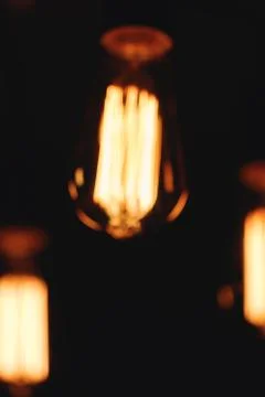Blurred image of glowing retro light bulbs at night. Stock Photos