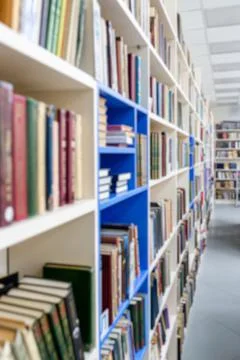 Blurred image of a library with bookcases. Many different books on the shelve Stock Photos