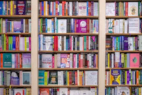 Blurred image of a library with bookcases. Many different books on the shelve Stock Photos