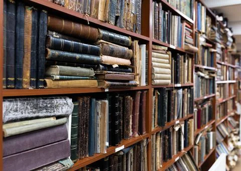 Blurred image of a library with bookcases. Many different books on the shelves Stock Photos