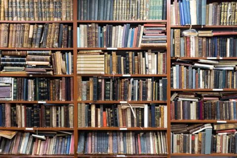 Blurred image of a library with bookcases. Many different books on the shelves Stock Photos