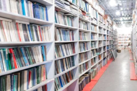 Blurred image of a library with bookcases. Many different books on the shelves Stock Photos