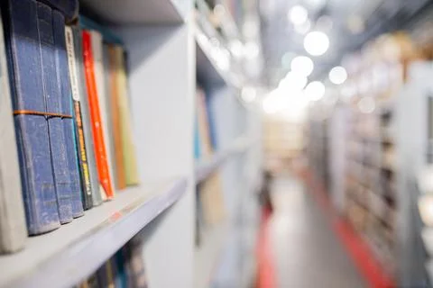 Blurred image of a library with bookcases. Many different books on the shelves Stock Photos