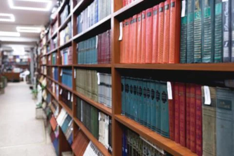 Blurred image of a library with bookcases. Many different books on the shelves Stock Photos